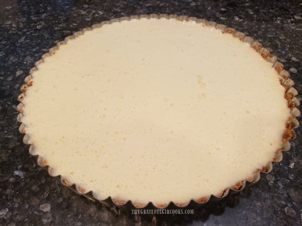 The tart crust is covered with the lemon cream cheese filling and then baked.