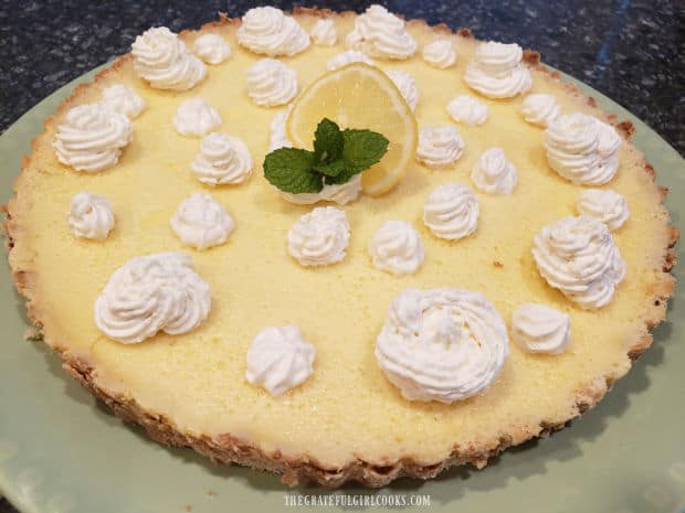 Lemon Cream Cheese Tart, garnished with whipped cream, lemon slice and mint leaf.