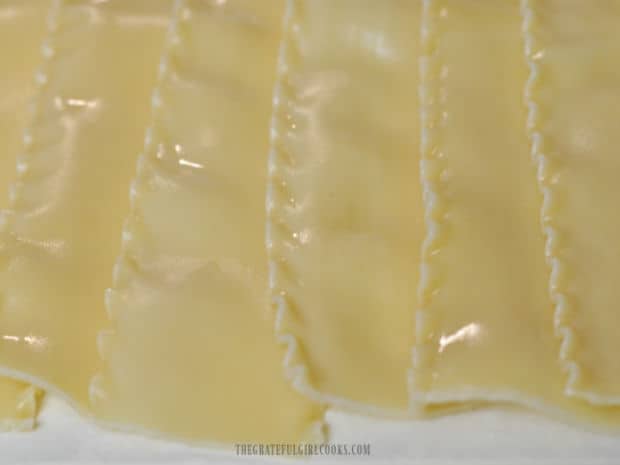 Lasagna noodles are cooked, then drained on paper towels.