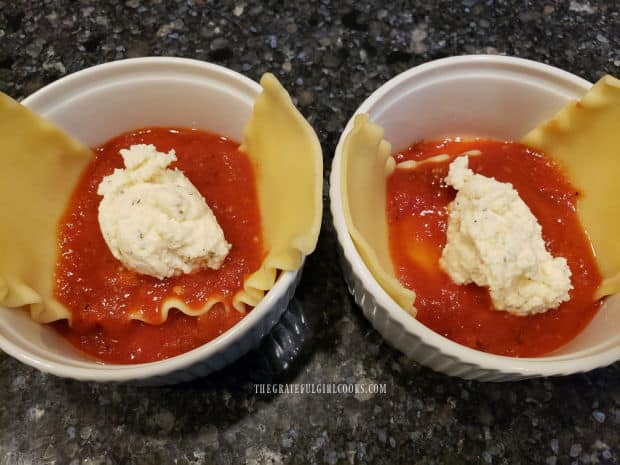 Marinara sauce and a seasoned ricotta cheese mixture is layered into the lasagna bowls.