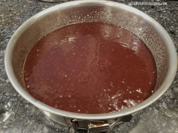 Mint brownie pie batter is poured into a greased springform pan.
