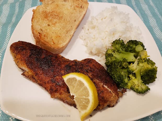 A serving of skillet grilled rockfish on a plate with broccoli, rice and garlic bread.