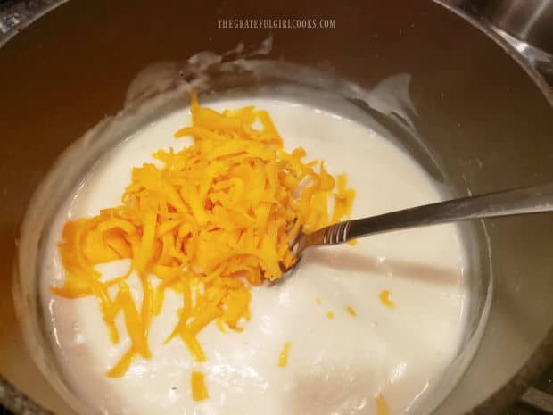 After sauce has thickened, sharp cheddar cheese is added, and stirred in, until fully incorporated.
