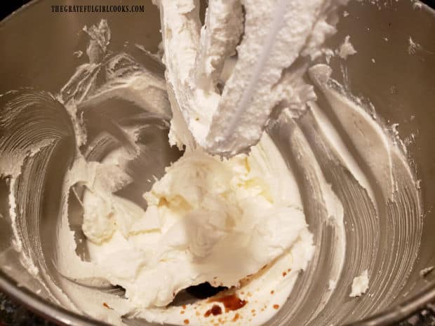 Vanilla extract is added to the frosting mixture in stand mixer.