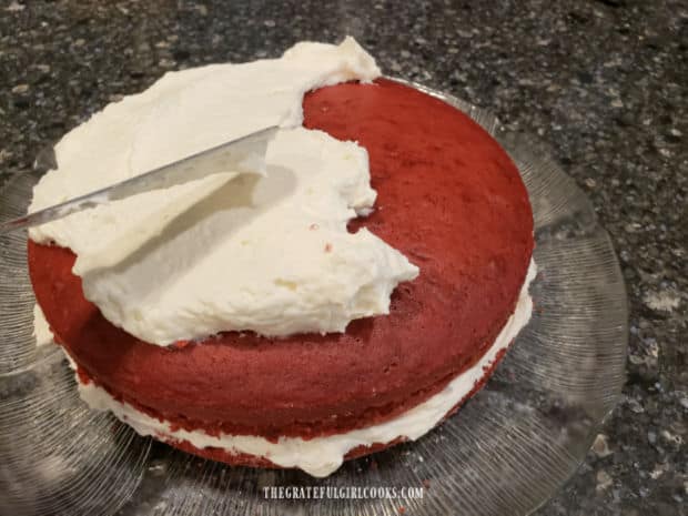 Spreading Grandma's Fluffy White Frosting onto a red velvet cake.