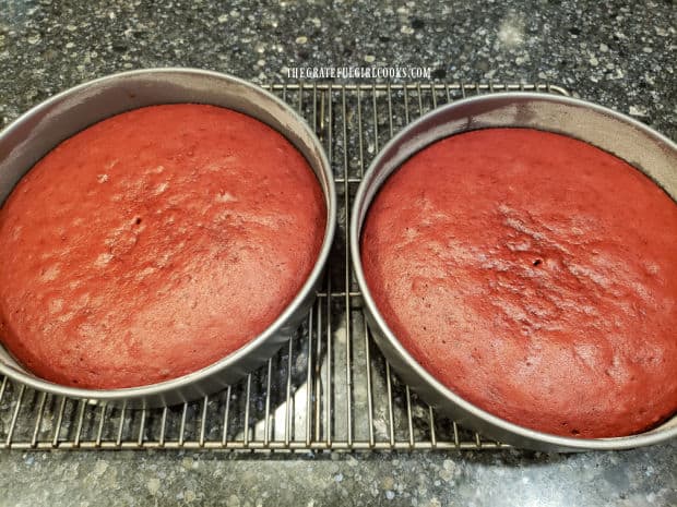 Two pans of red velvet cake cooling on wire racks after baking.