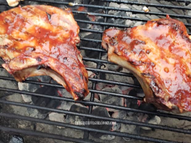 Pork chops on the grill, coated with the honey BBQ sauce.