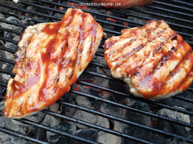 Pieces of chicken brushed with homemade honey BBQ sauce, cooking on the grill.