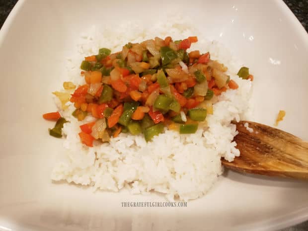 A white bowl with the cooked veggies added on top of cooked white rice.