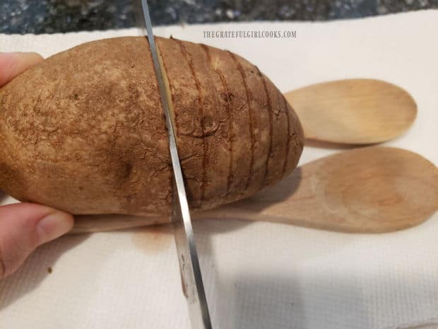 Thin slices are cut in each potato, almost all the way through to the bottom.