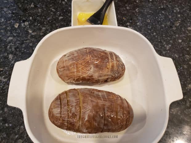 Melted butter and salt are added to the potatoes in a baking dish before roasting.