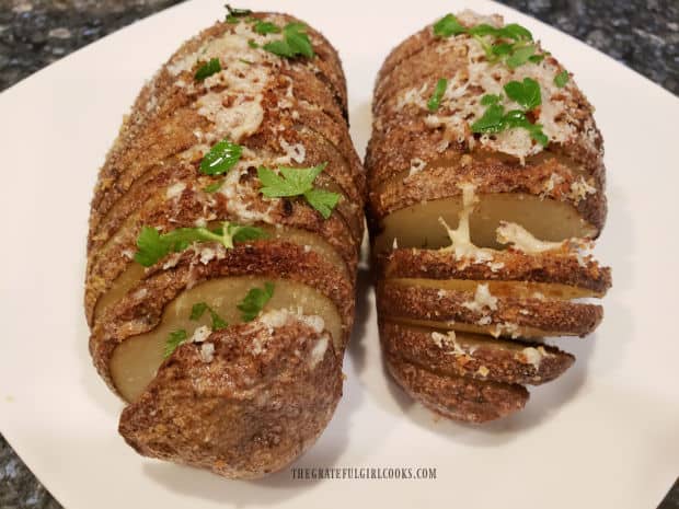 The roasted Hasselback potatoes are served, garnished with chopped parsley.