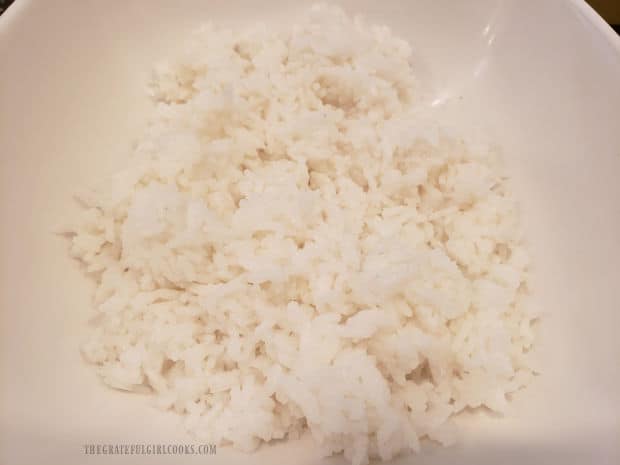 Cooked rice is rinsed then drained before adding it to salad bowl.