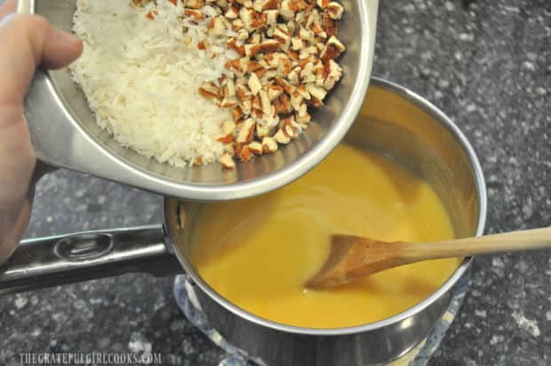 Shredded coconut and chopped pecans are added to saucepan.