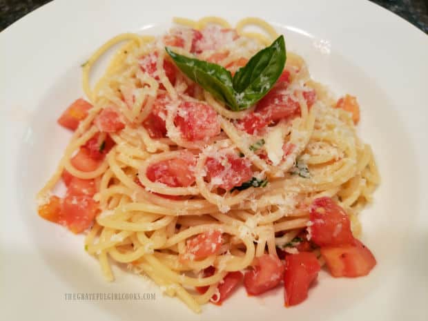 The tomato basil pasta is garnished with grated Parmesan cheese and basil leaves before serving.