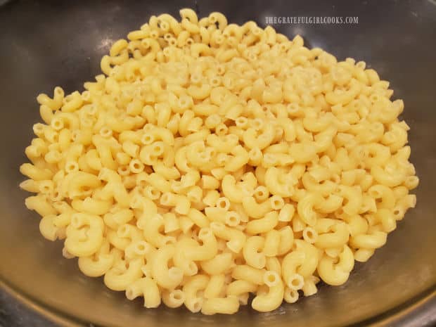 Macaroni pasta is cooked, drained, then placed in a large mixing bowl.