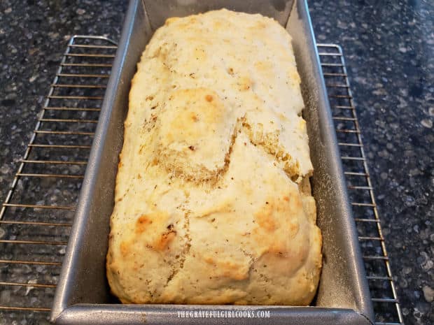 A loaf of golden brown sun-dried tomato Parmesan bread cools in pan after baking.