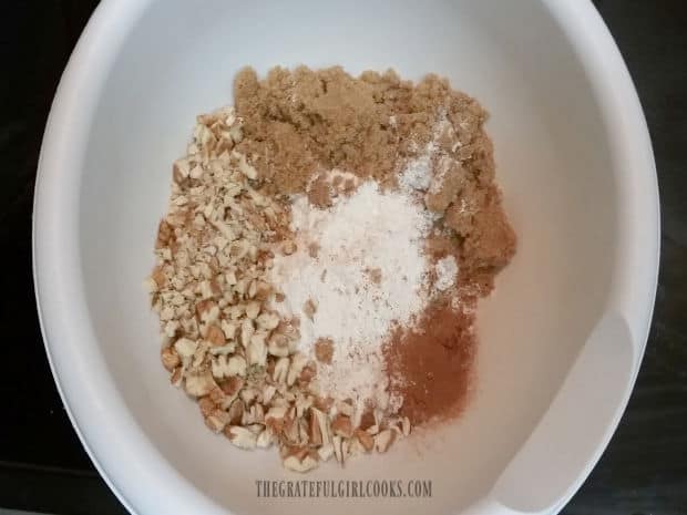 Flour, brown sugar, cinnamon, and pecans in a bowl to make streusel topping for pie.