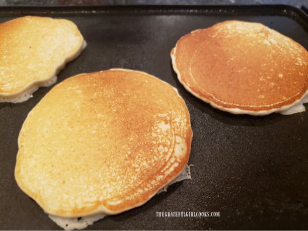 Easy buttermilk pancakes cooking on an electric griddle.