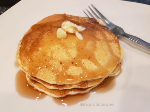 A stack of three easy buttermilk pancakes, topped with butter and maple syrup.