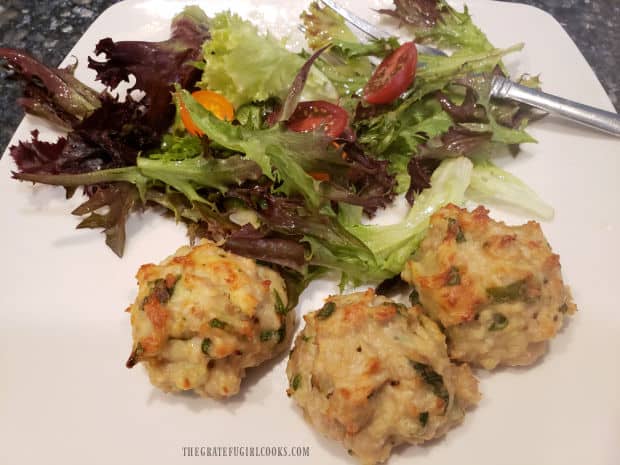 Three Italian Chicken Parmesan Meatballs on a plate with a mixed green salad on the side.