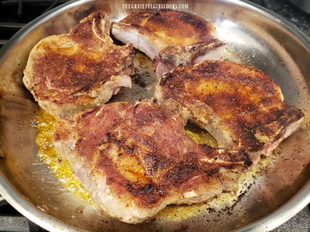 Both sides of the pork chops are browned well in a large skillet.