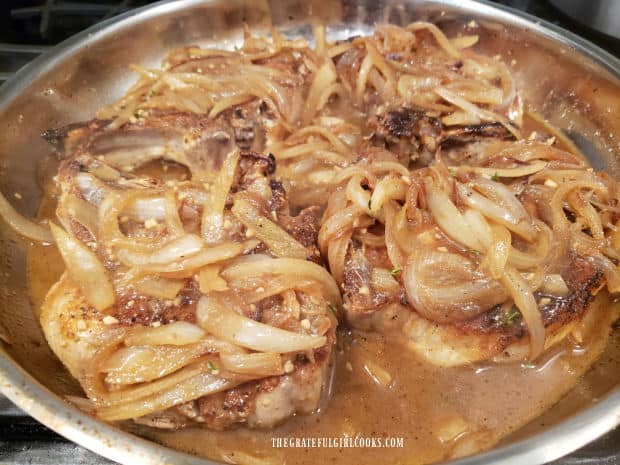 Smoked smothered pork chops are covered with gravy and cooked onions.
