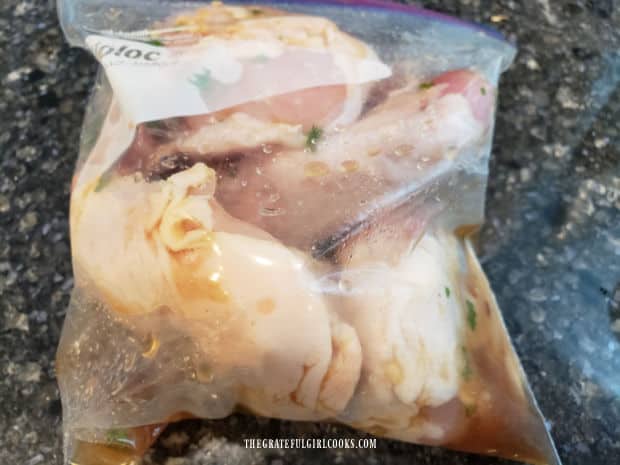 Four chicken thighs are soaking in the marinade in a re-sealable bag for several hours.