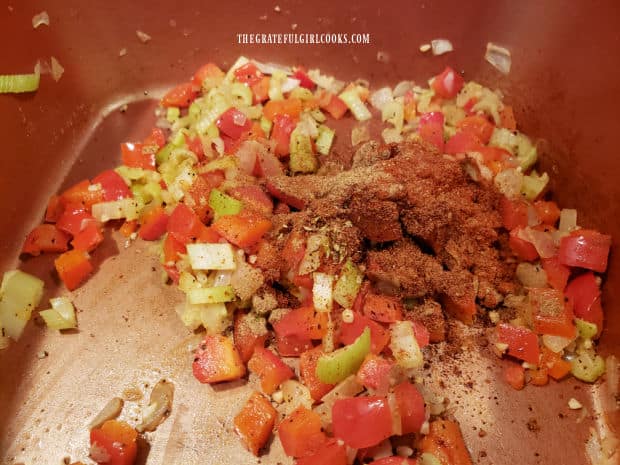 Homemade seasoning mix is added to the sautéed veggies in the saucepan.