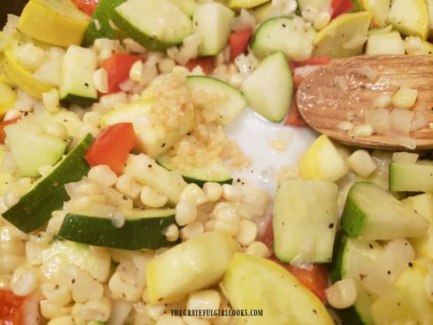 Minced garlic and a small amount of milk are added to the cooking veggies.