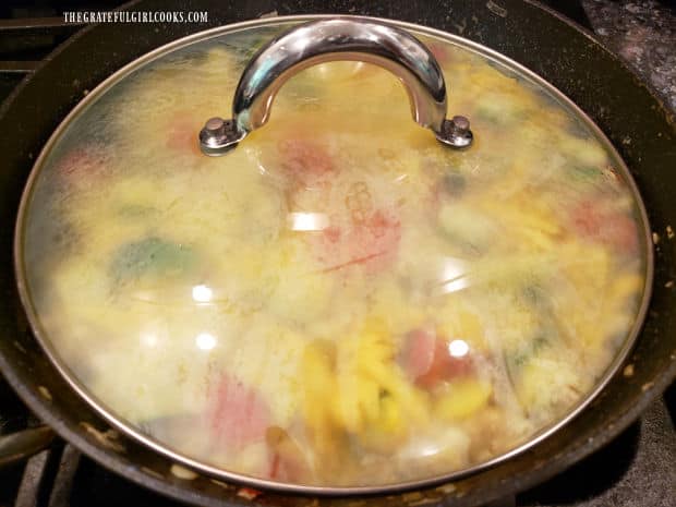 A lid is placed on the skillet to allow the cheese a minute to melt on top of the vegetables.