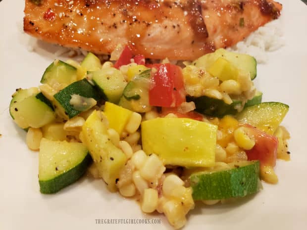 A serving from the TexMex Zucchini Squash skillet, placed on a plate with rice and salmon.