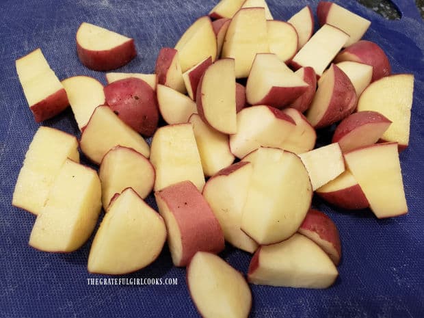 The unpeeled red potatoes are cut into bite sized chunks before seasoning.