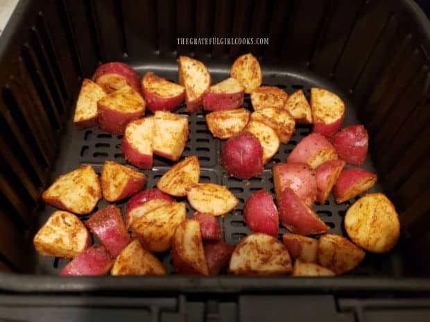 The potatoes are placed in an air fryer basket in a single layer.