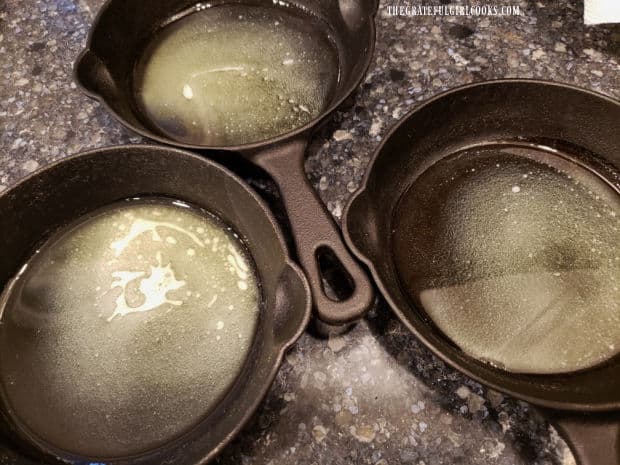 Melted butter is divided between three 6" cast iron mini skillets.