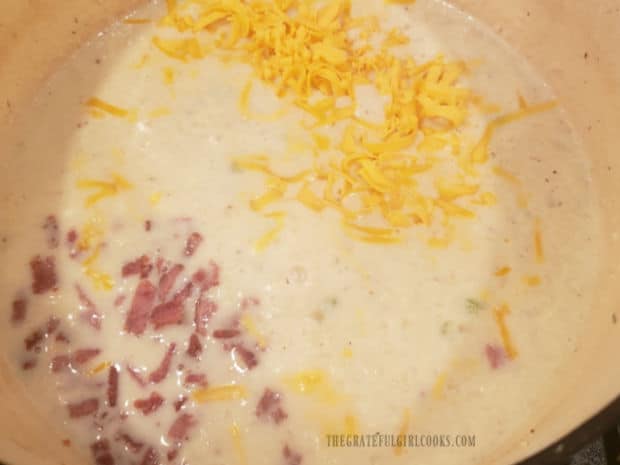 Bacon pieces and shredded cheese are added to the hot chowder.