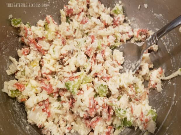 The filling for cheesy calzone pinwheels is stirred until fully combined.