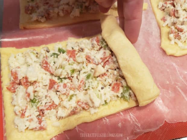 Each filled calzone dough rectangle is rolled up, starting at short side.