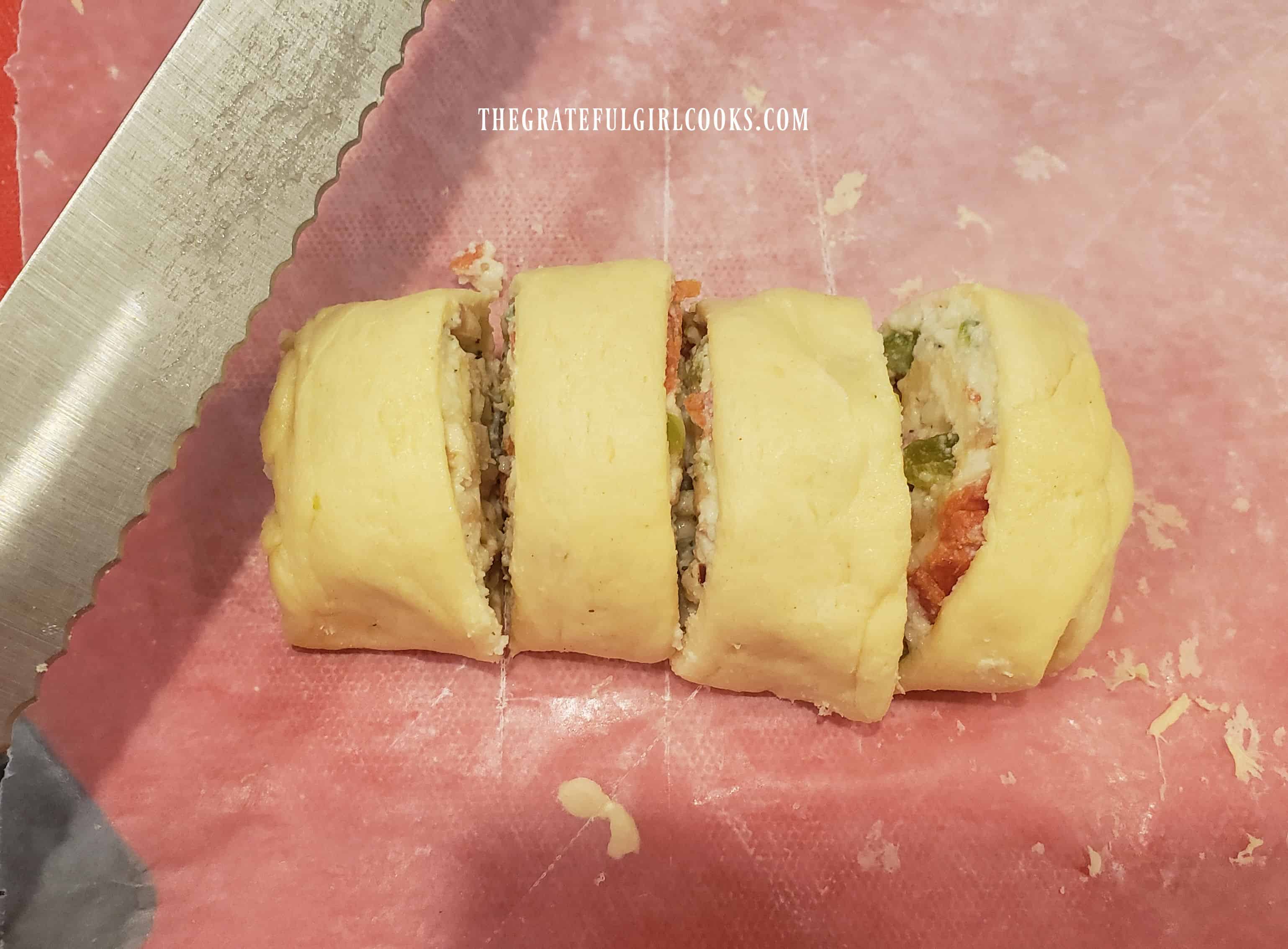 Each of the calzone rolls are cut into four slices with a serrated knife.