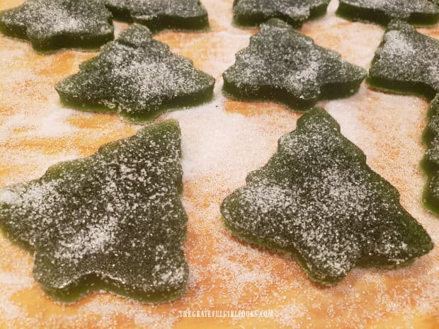 The finished Christmas tree gumdrops are allowed to sit and dry slightly on the sugar coated board.