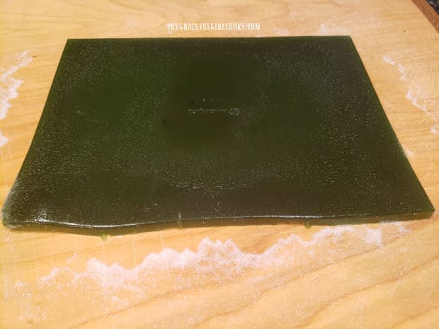 The entire baking pan full of lime gelatin is flipped onto a sugar coated cutting board.