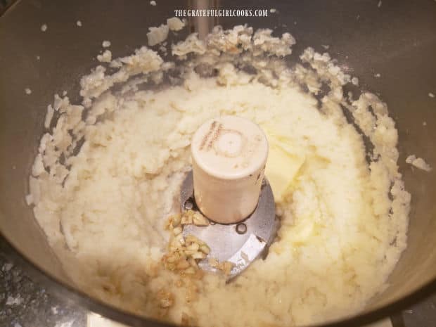 Butter and chopped garlic are added to pureed cauliflower in a food processor.