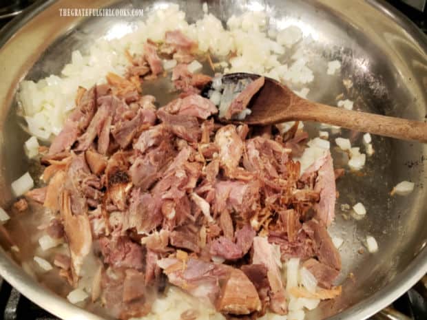 Shredded (or cubed) ham is added to the cooked onions in the skillet.