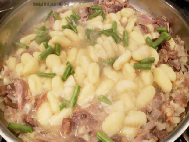 Potato gnocchi and sliced green beans are added to the skillet.