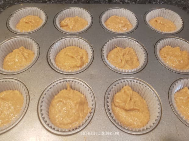 The muffin batter is evenly divided into 12 paper-lined muffin cups.