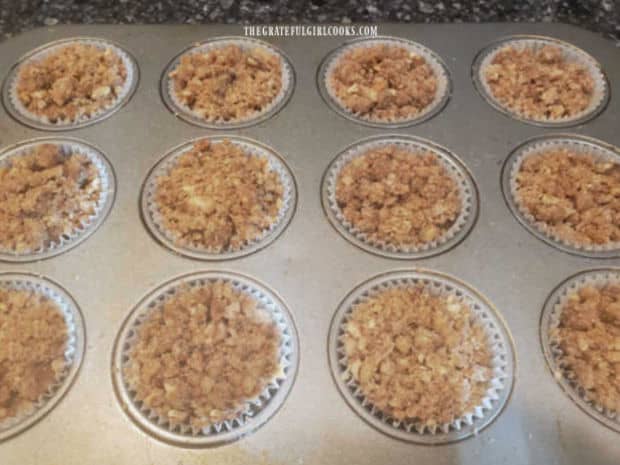 Each of the cups of pumpkin muffin batter is topped with pecan streusel before baking.
