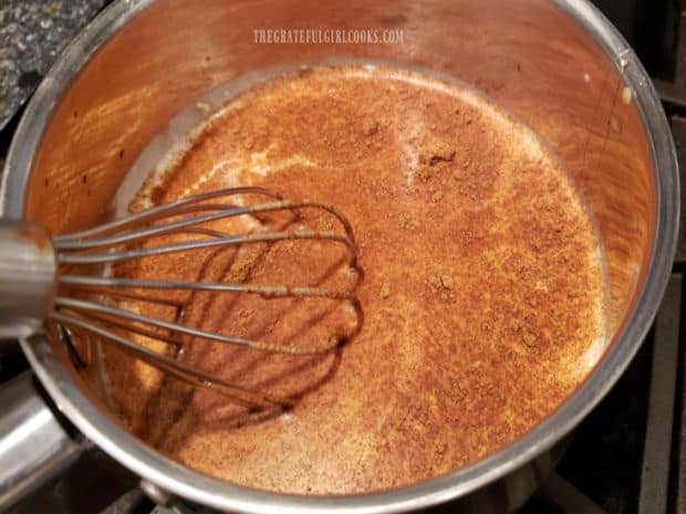 Whisking and cooking the pumpkin spice coconut milk latte until hot in a saucepan.