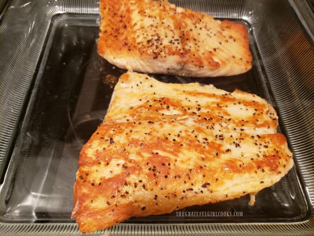Browned salmon fillets are baked in the oven after pan-searing.