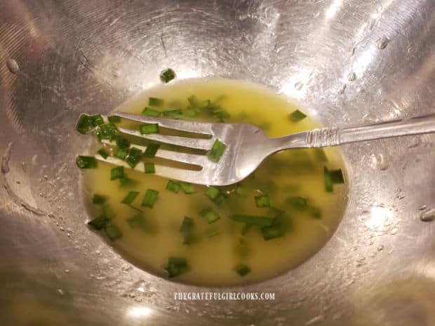 A small bowl, holding the lemon chive drizzling oil to top the salmon fillets.