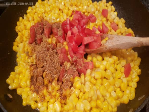 Seasoning mix and chopped Roma tomatoes are added to corn in skillet.